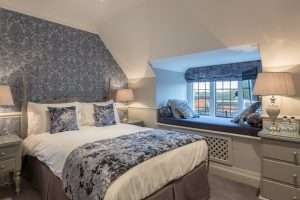 Standard Manor Room at Greenwoods Hotel with elegant blue theme, double bed, and cozy window seating area overlooking the grounds.