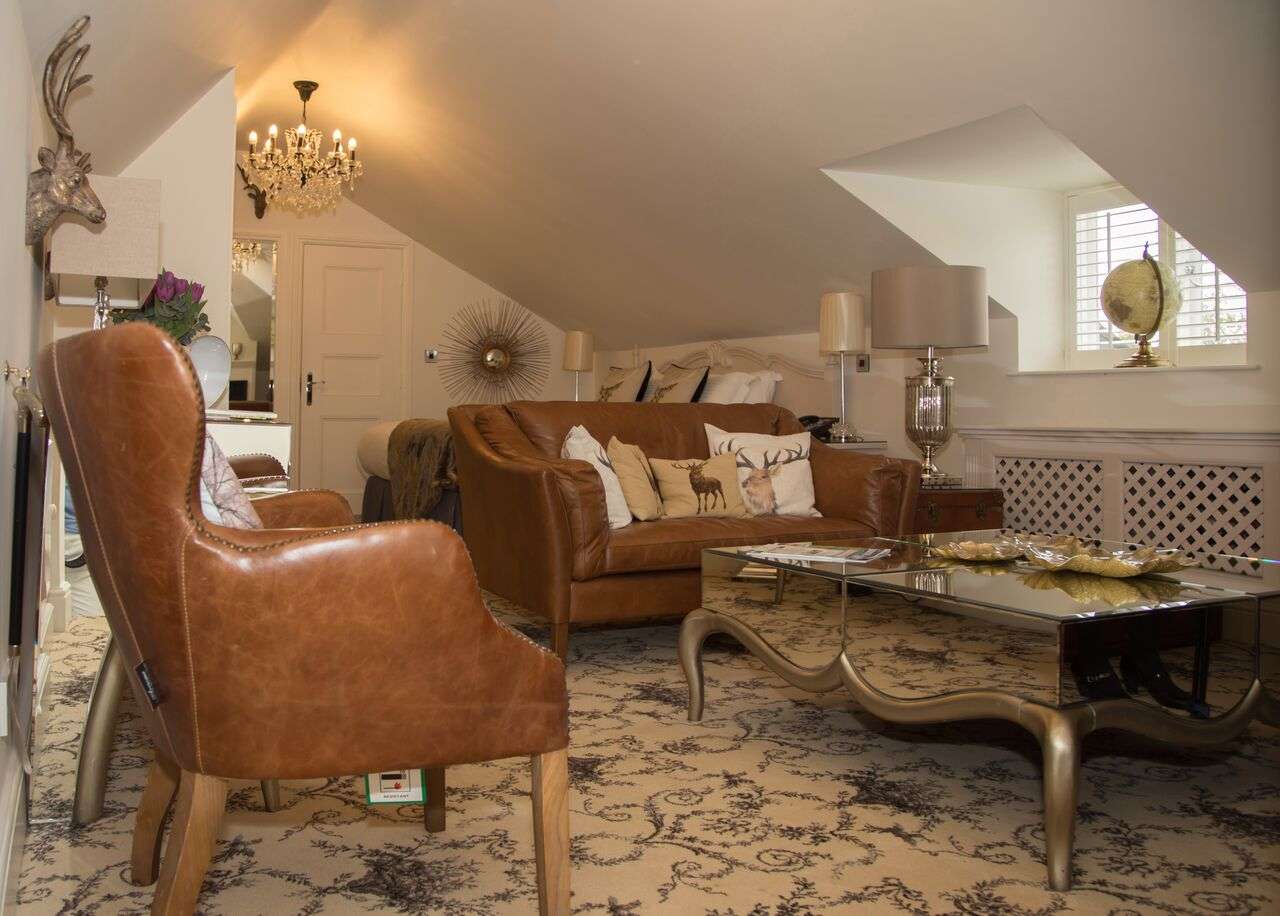 Elegant attic suite with leather chairs and mirrored table at Greenwoods Hotel and Spa.
