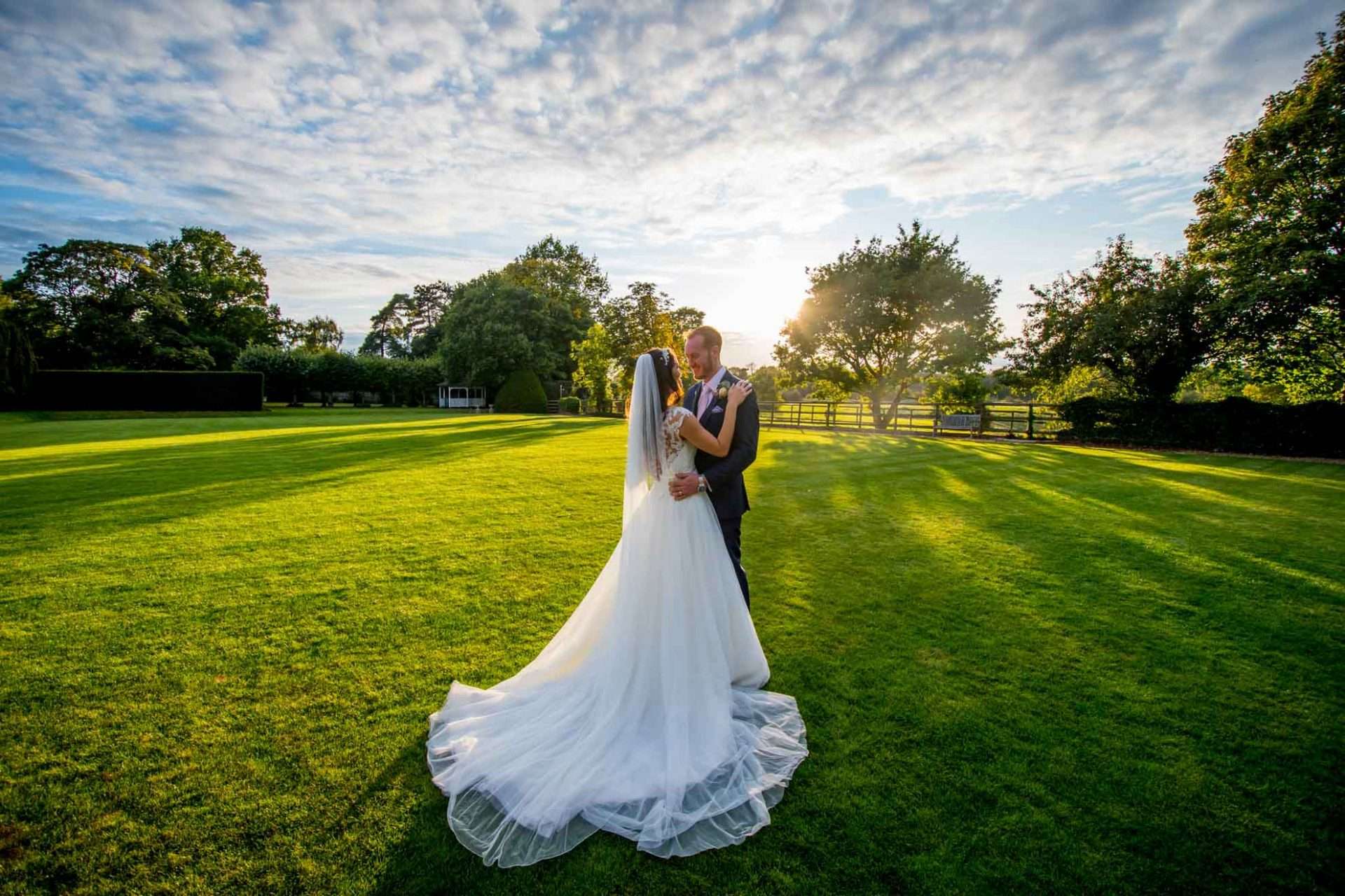 Bride and groom standing in the field at sunset at Greenwoods Hotel wedding venue in Essex
