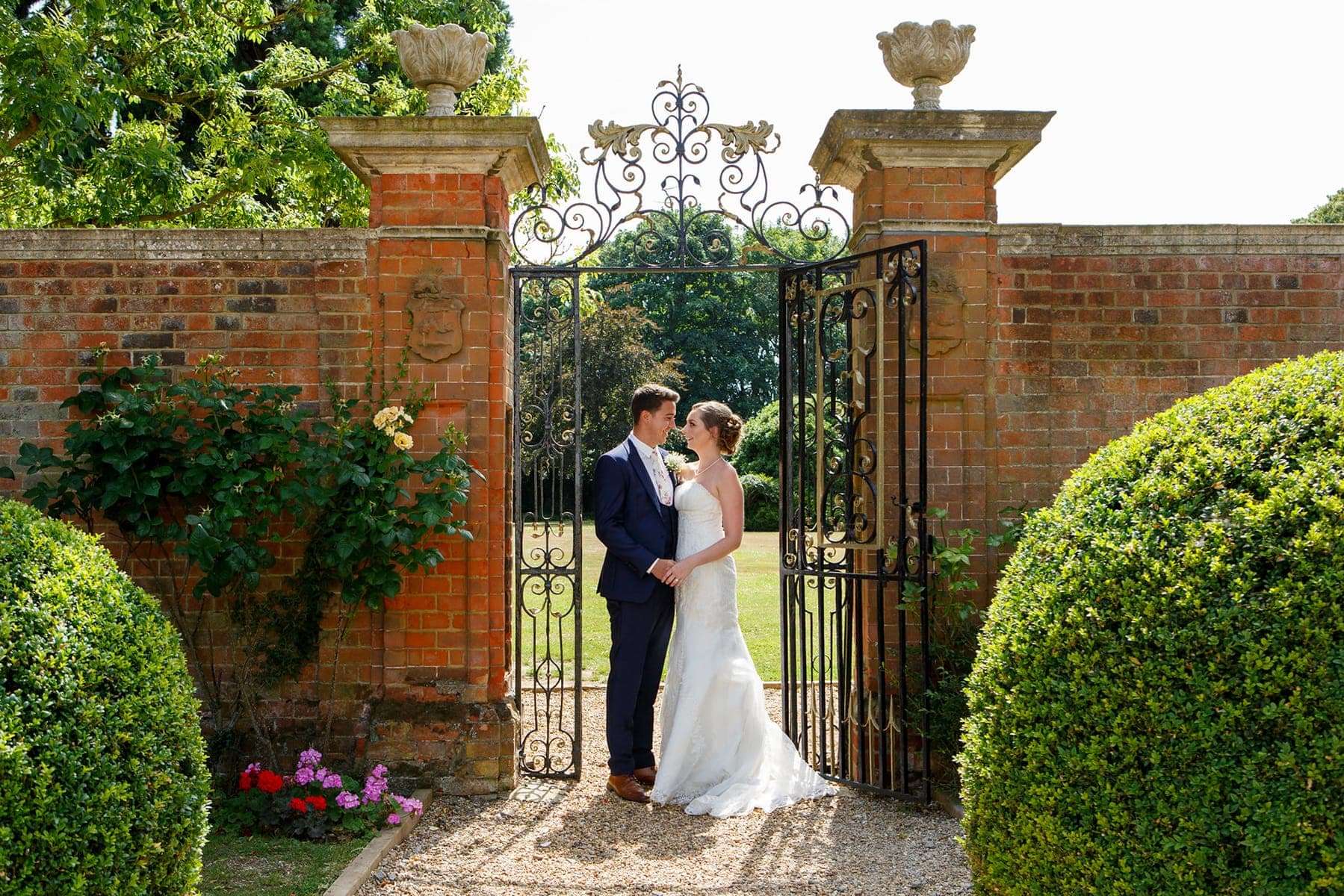 Newlyweds captured beside the ornate walled garden gate at Greenwoods Hotel during their Essex wedding