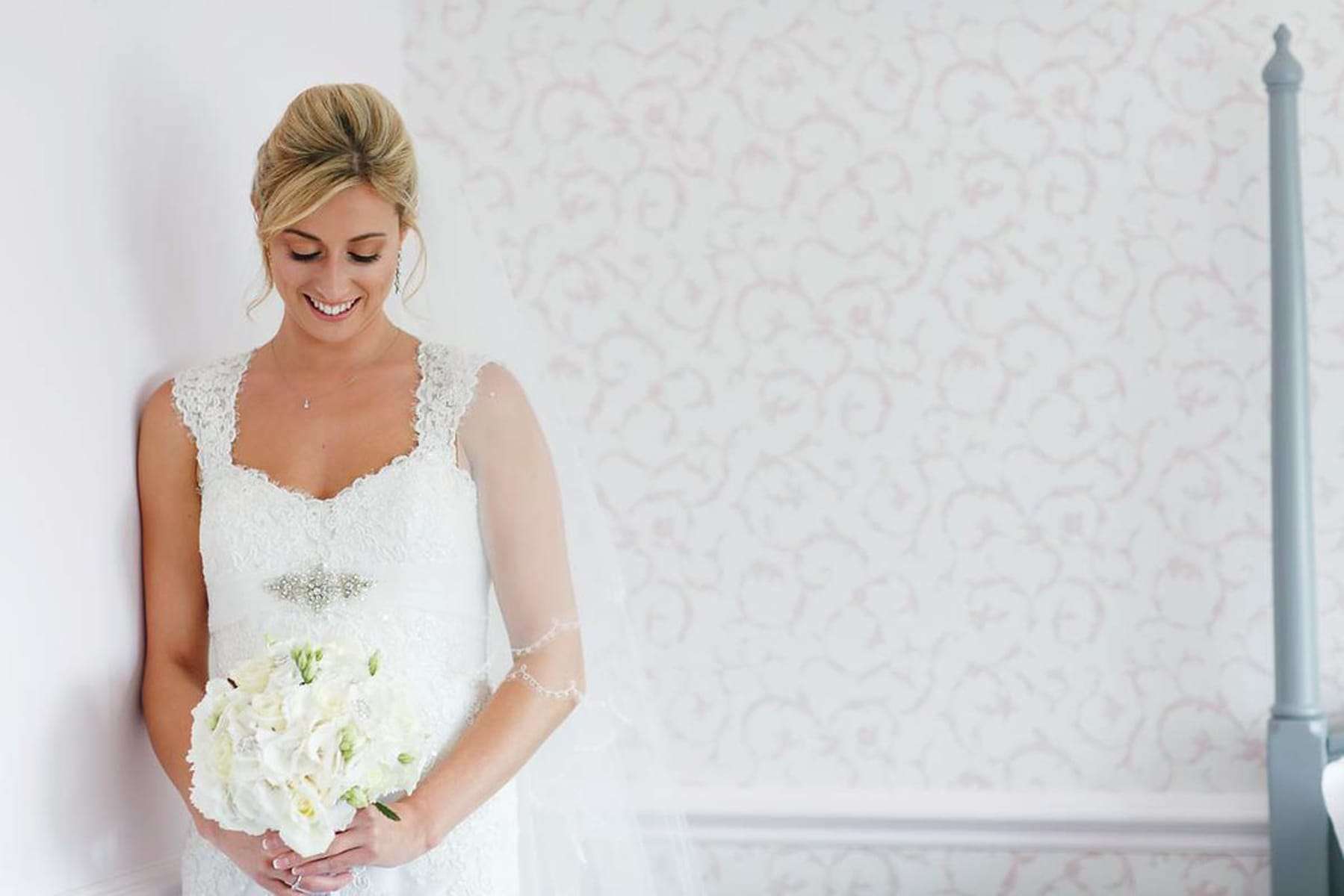 Bride holding white bouquet and smiling before wedding ceremony at Greenwoods Hotel & Spa