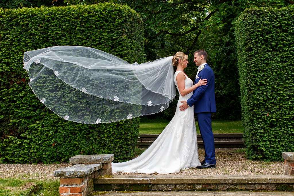 Bride and groom outside with flowing veil on wedding day at Greenwoods Hotel in Essex