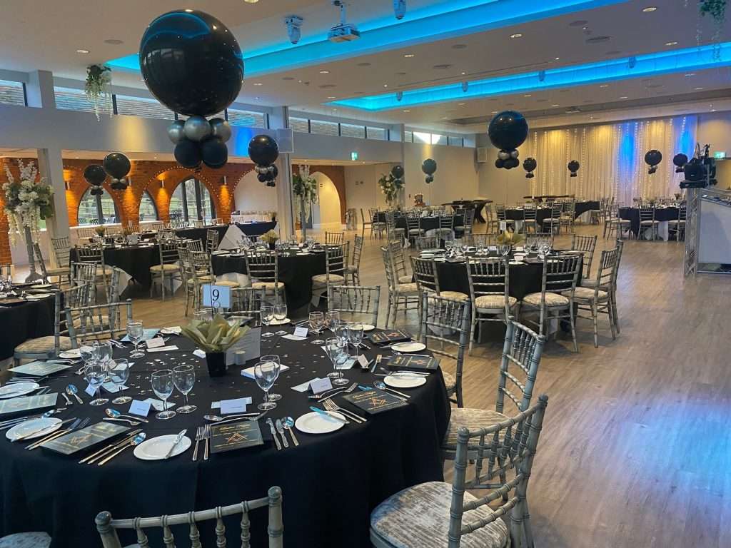 Elegant black and silver themed charity ball setup in the Garden Suite at Greenwoods Hotel with overhead blue lighting.