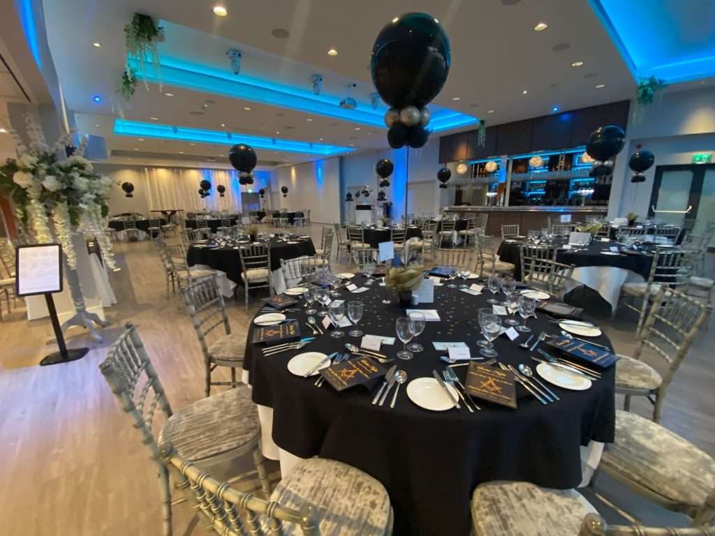 Charity gala event in the Garden Suite with black tablecloths, silver chairs, and dramatic lighting décor.