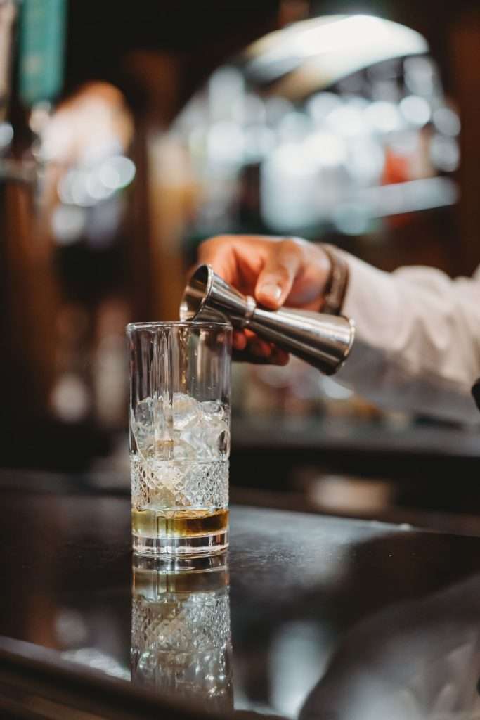 Bartender pouring a cocktail in the Lounge Bar at Greenwoods Hotel, showcasing the refined bar experience in Essex.