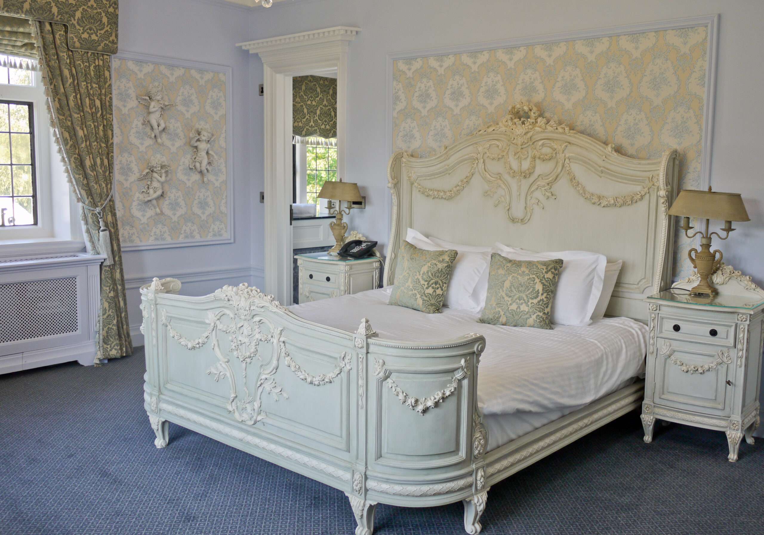 Deluxe room at Greenwoods Hotel with decorative cherubs and green classical styling