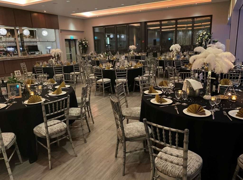 Charity ball event layout in the Garden Suite featuring black linens and gold accents with elegant glassware.