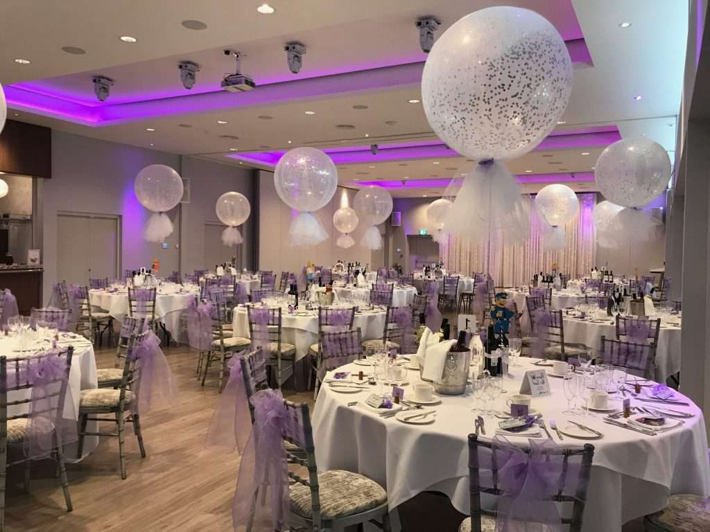 Charity ball in the Garden Suite at Greenwoods Hotel, decorated in lilac hues with round banquet tables and giant balloons.