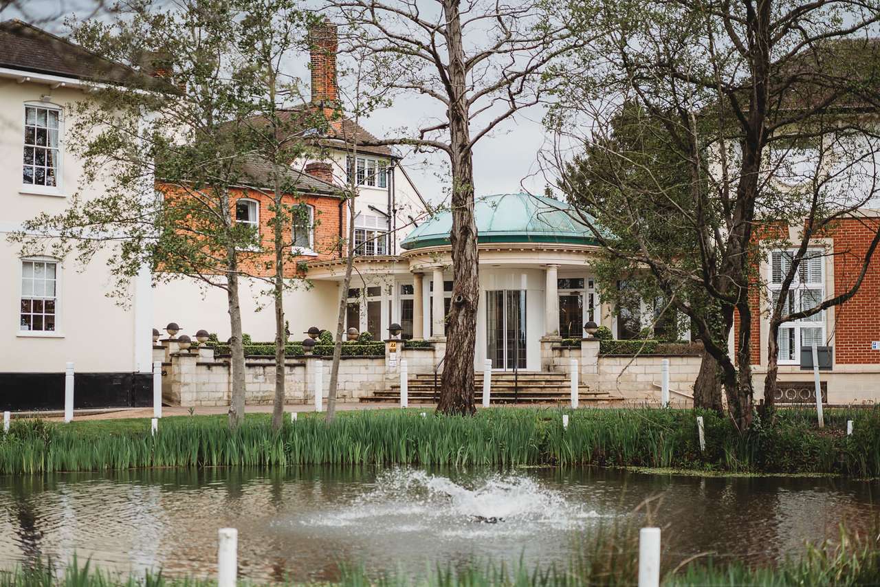 Front view of Greenwoods Hotel with pond and trees at entrance
