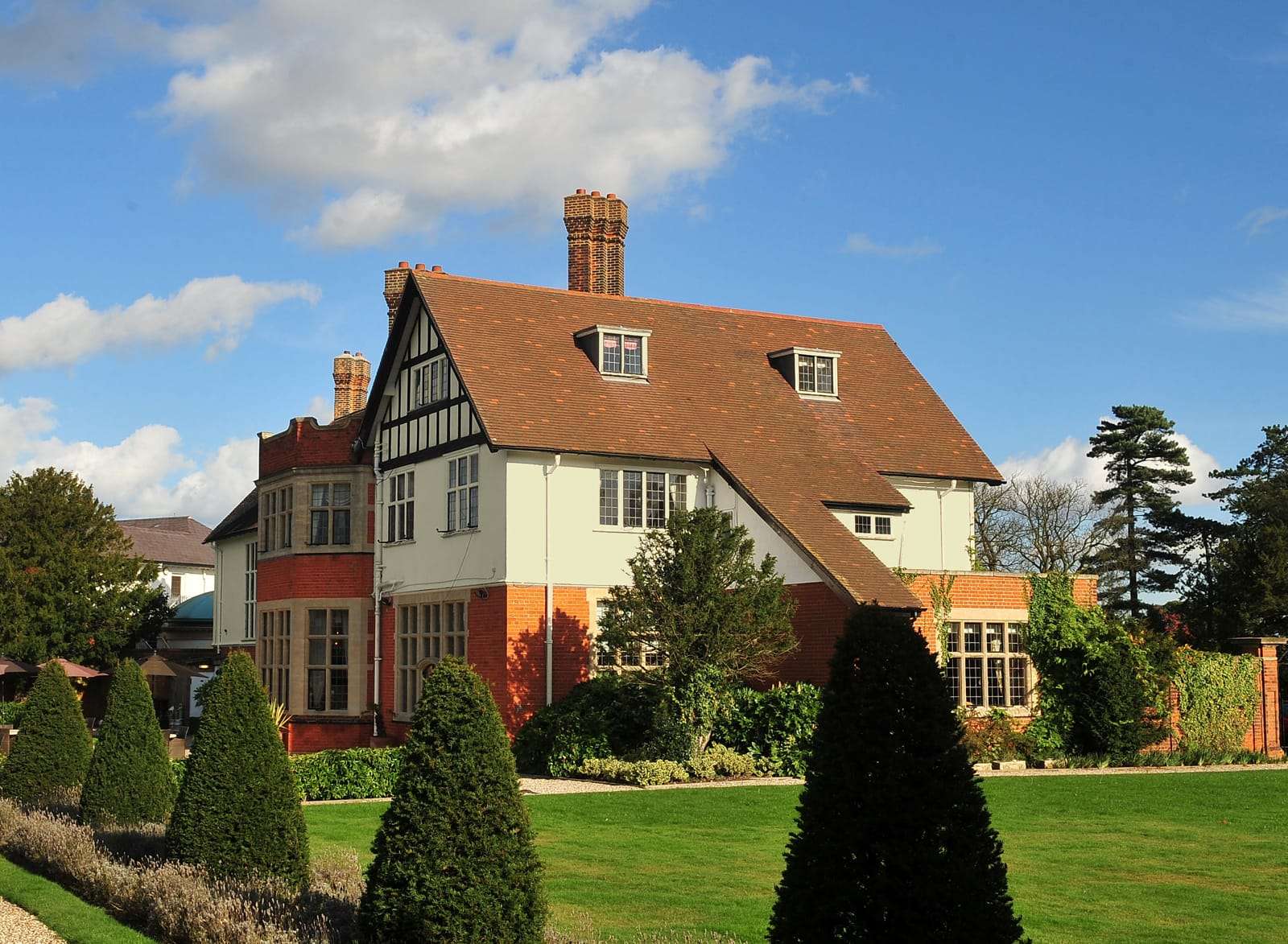 Rear exterior of Greenwoods Hotel with red brick and white façade on a sunny day