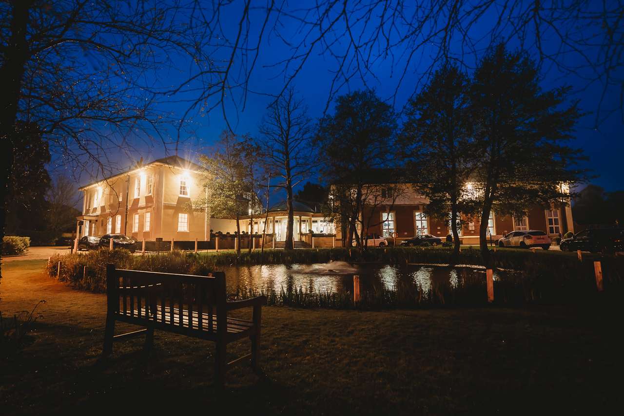 Exterior night shot of Greenwoods Hotel with pond and lighting