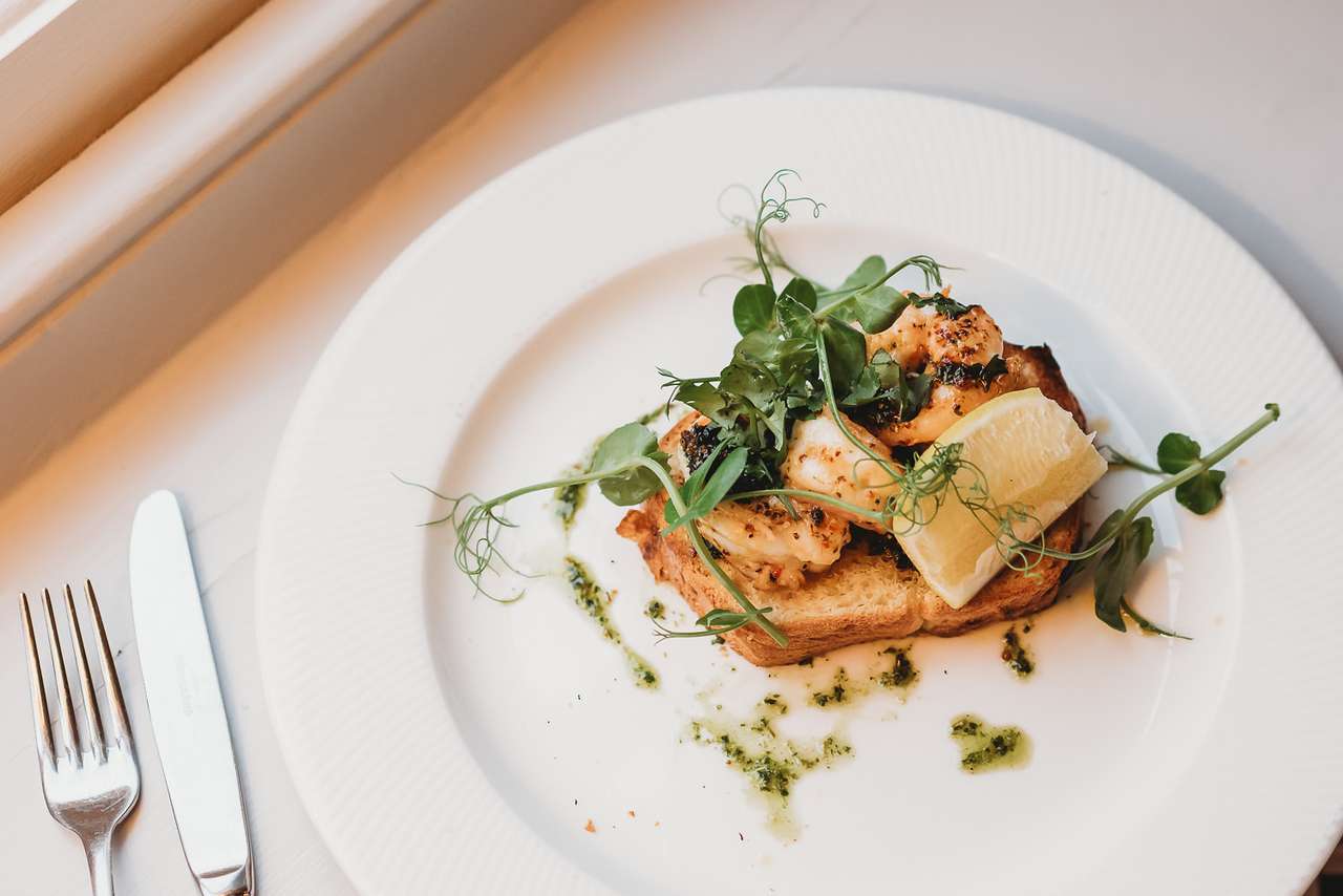 Delicious king prawn starter with lemon and herbs on white plate