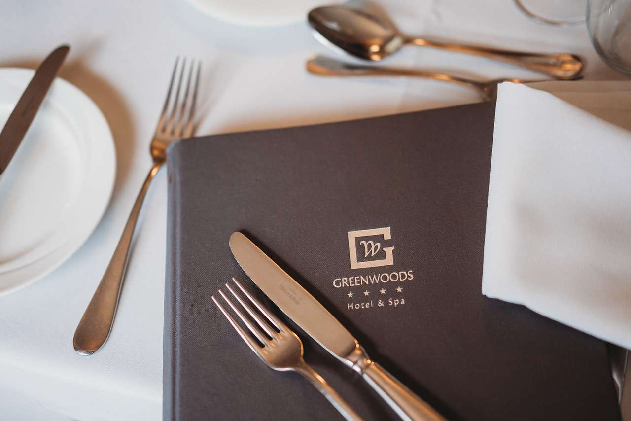 Branded Greenwoods Hotel & Spa menu on a formal dining table