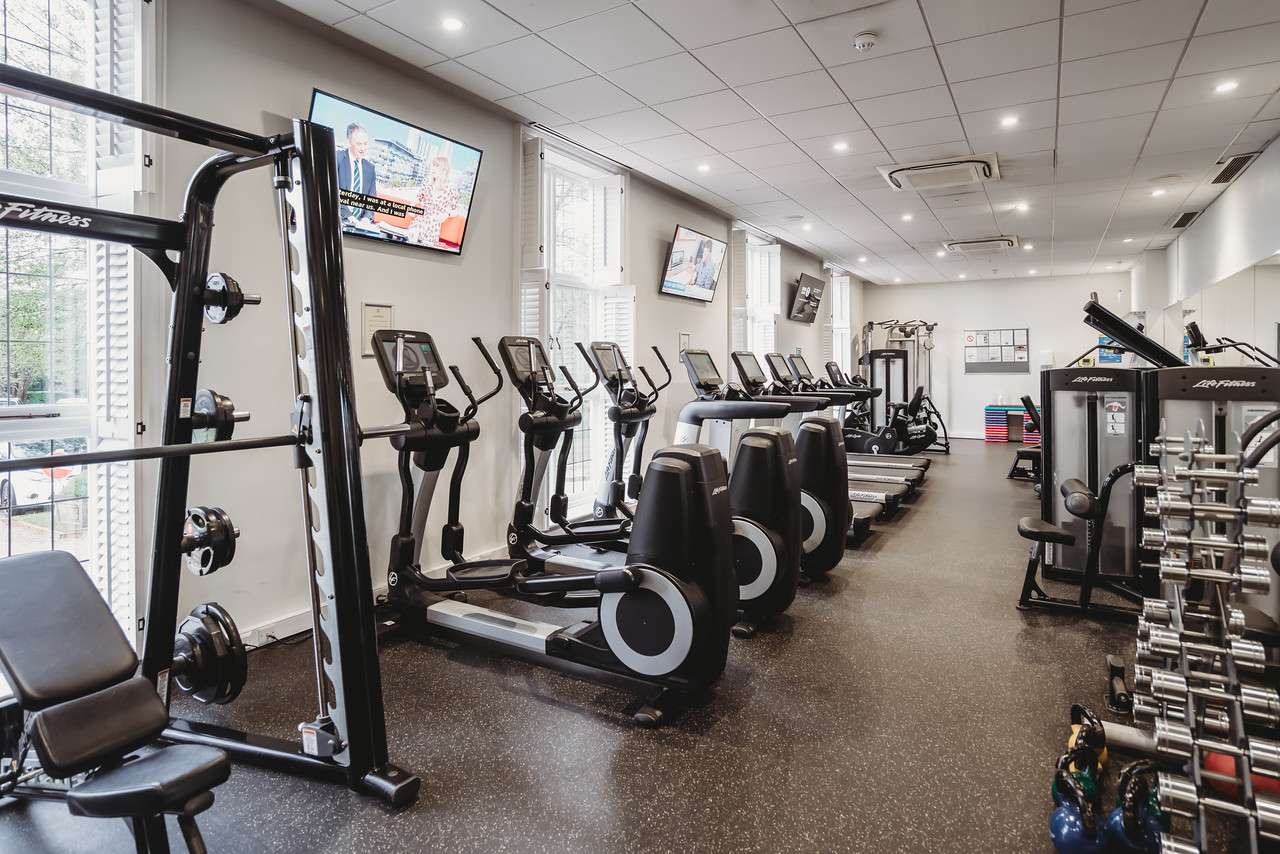 Spacious gym at Greenwoods Hotel with treadmills, ellipticals, and strength machines