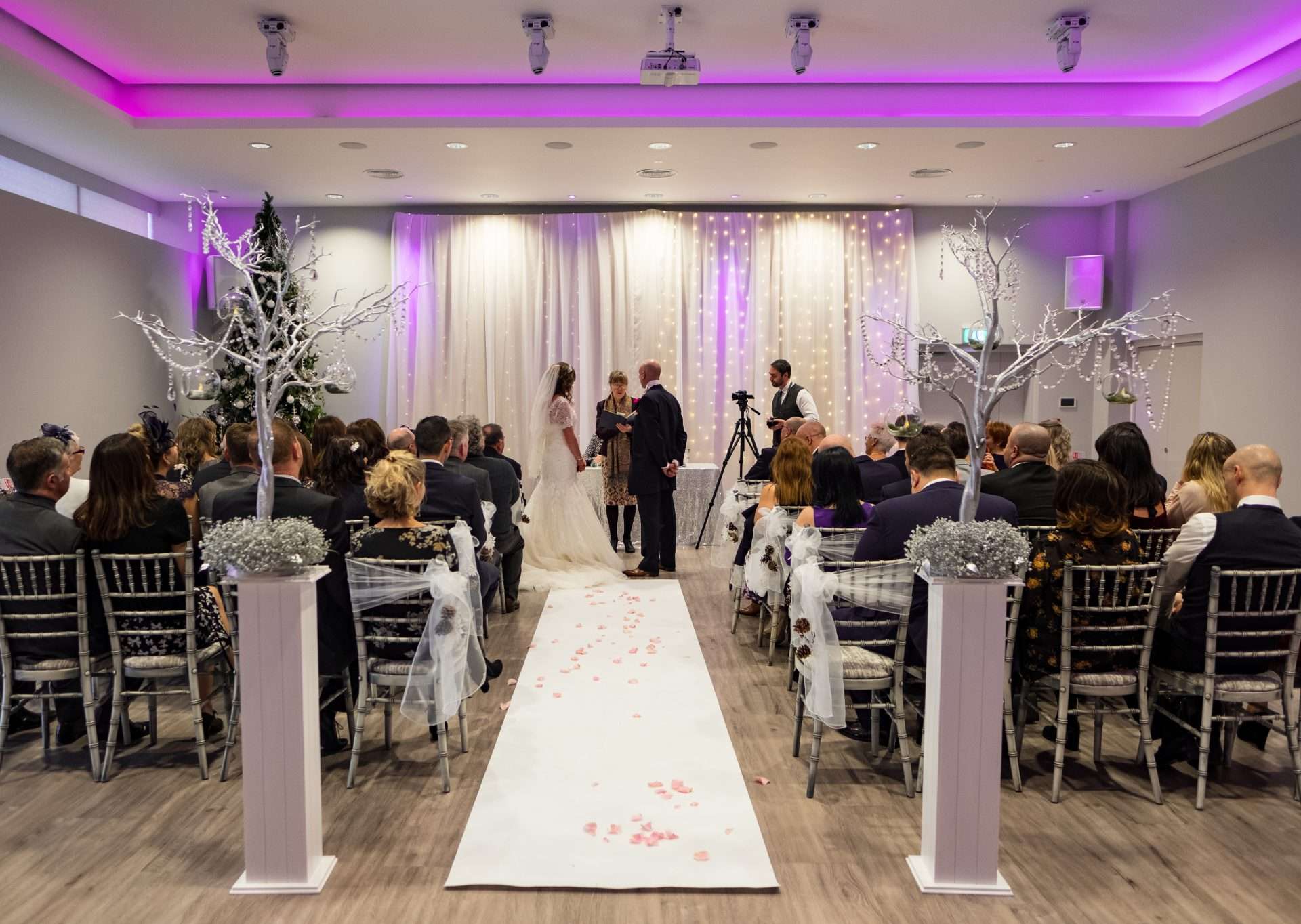 Indoor wedding ceremony at Greenwoods Hotel with fairy lights and winter-themed décor