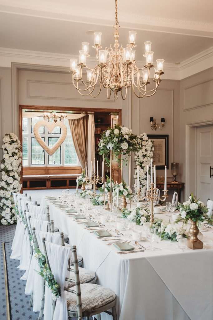 Bright daytime view of the Library Suite at Greenwoods Hotel, showing round table layout and traditional wood fireplace. Setup for Baby / Bridal Shower