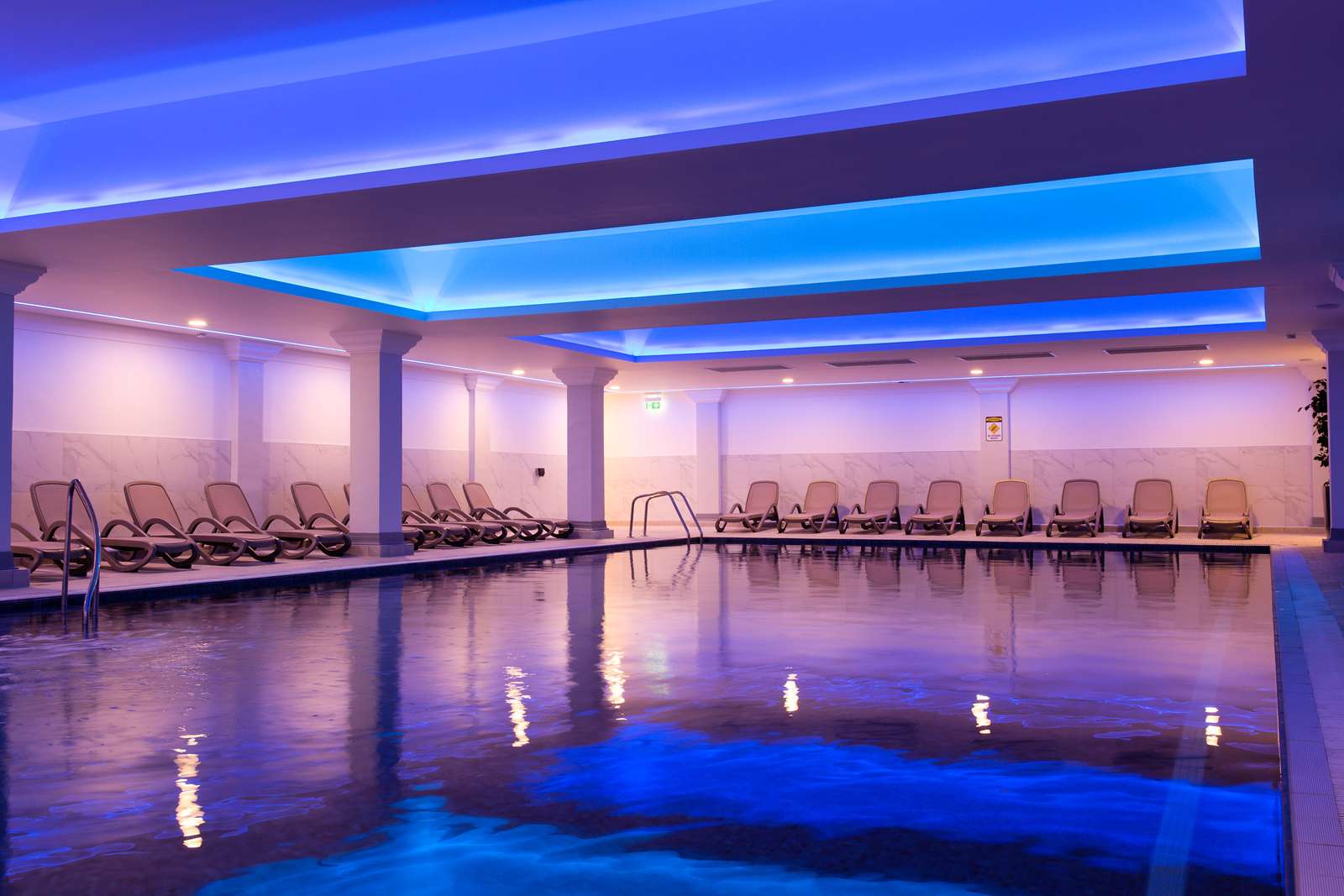 Tranquil indoor pool with loungers and blue mood lighting at Greenwoods Hotel Spa