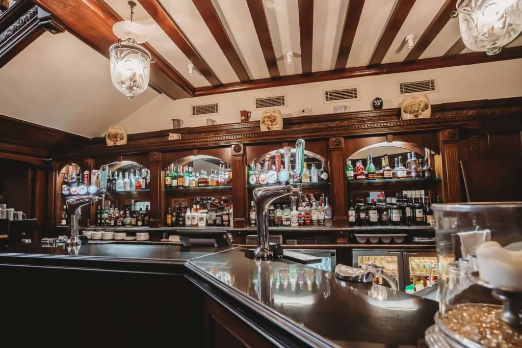 The main bar inside Greenwoods Hotel Lounge, showcasing a premium drinks selection and inviting traditional wood-panelled atmosphere.