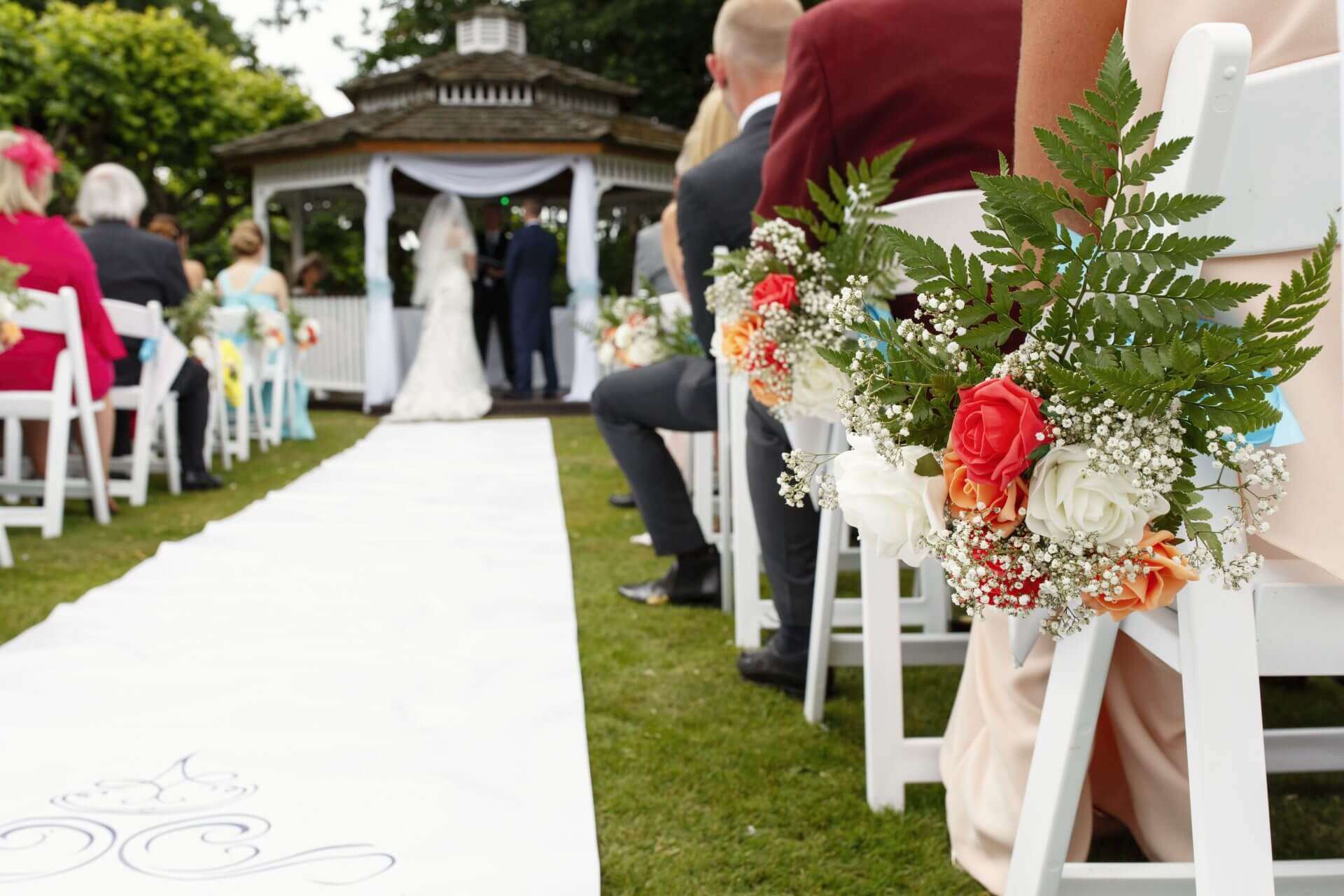 View down the aisle towards the couple marrying at the outdoor gazebo at Greenwoods Hotel wedding venue in Essex