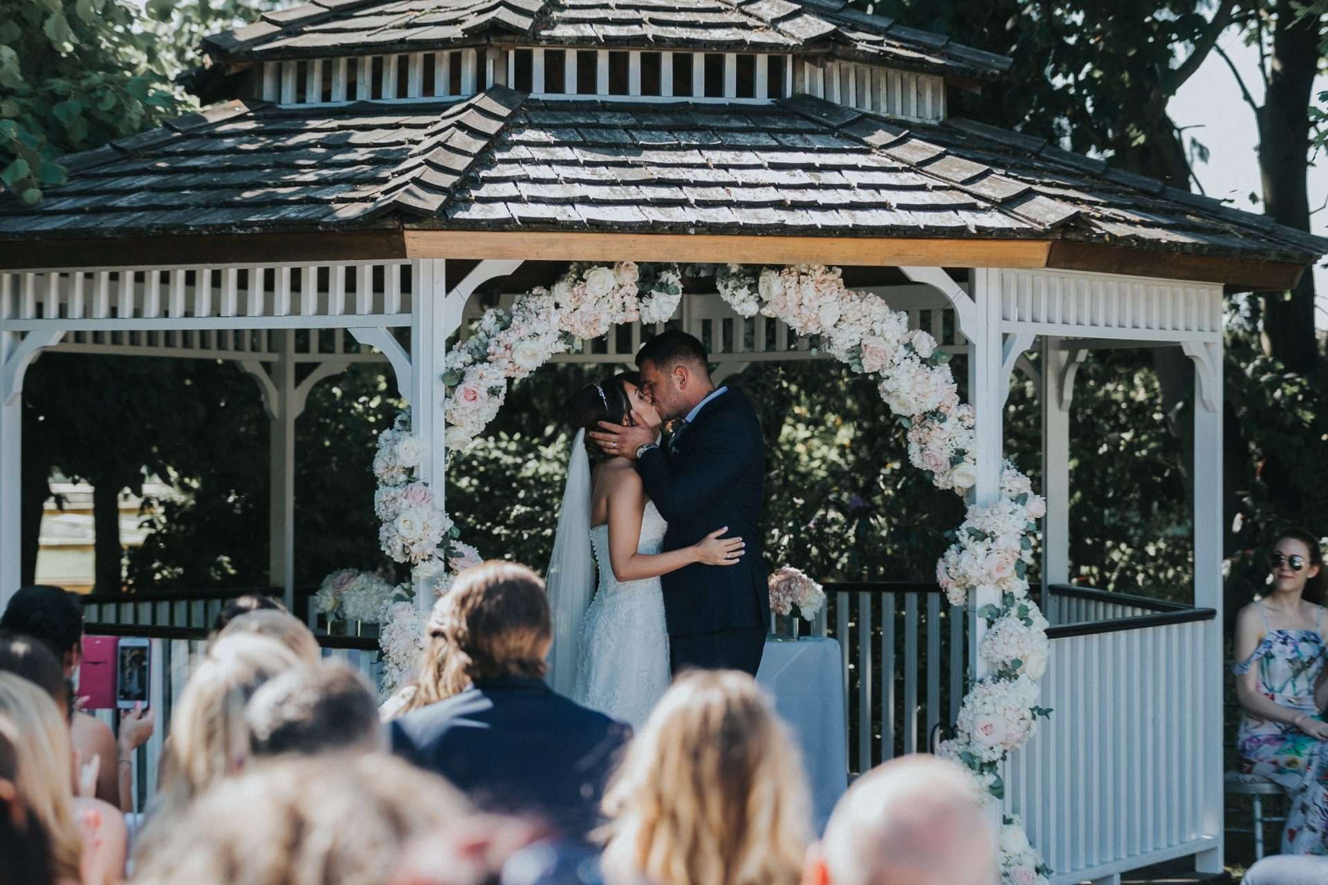 Wedding ceremony at the outdoor gazebo with the bride and groom kissing at Greenwoods Hotel in Essex