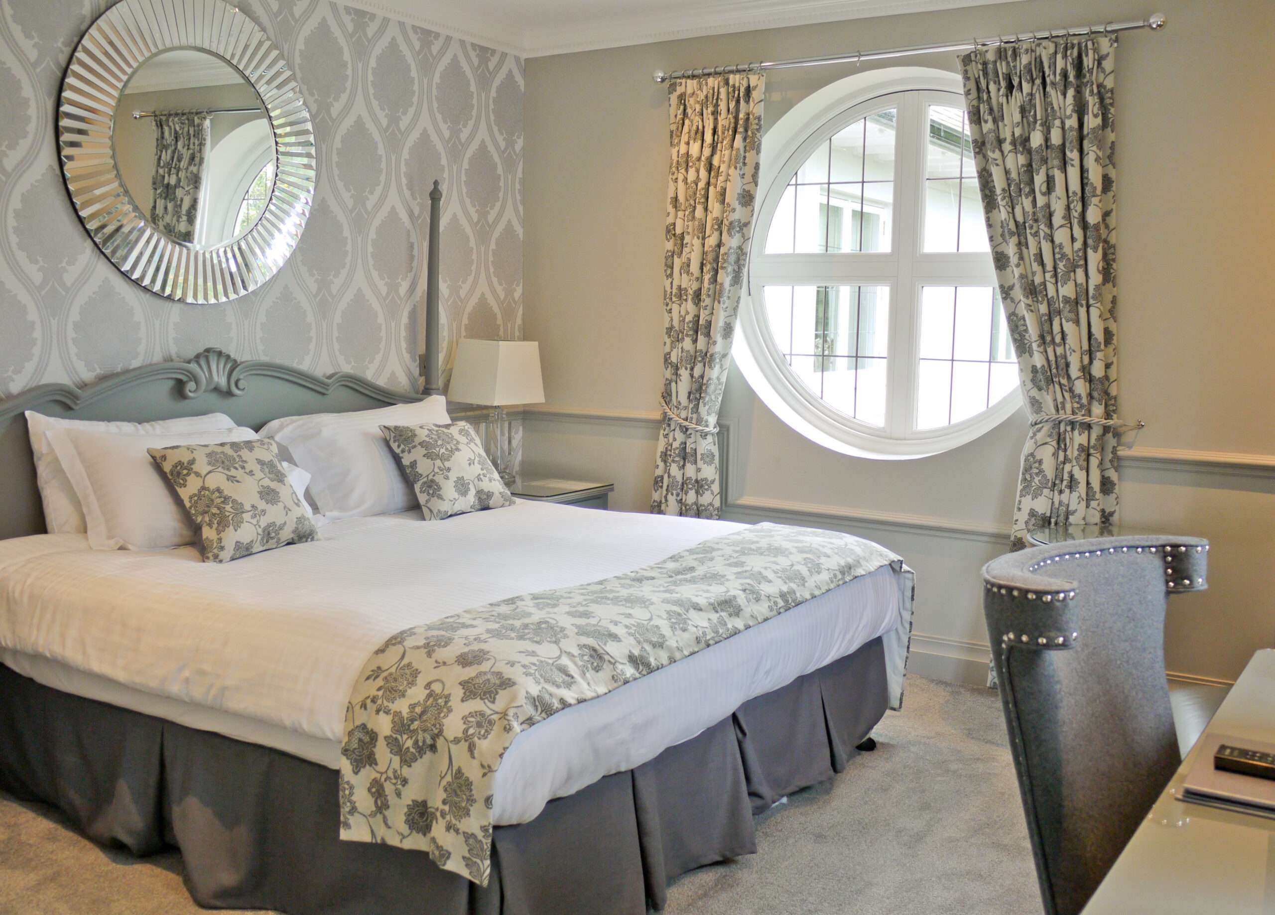 Premier room at Greenwoods Hotel with a unique round window and soft floral tones