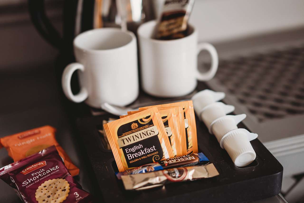 Close-up of welcome tray in Greenwoods Hotel room with tea, coffee, biscuits, and mugs.