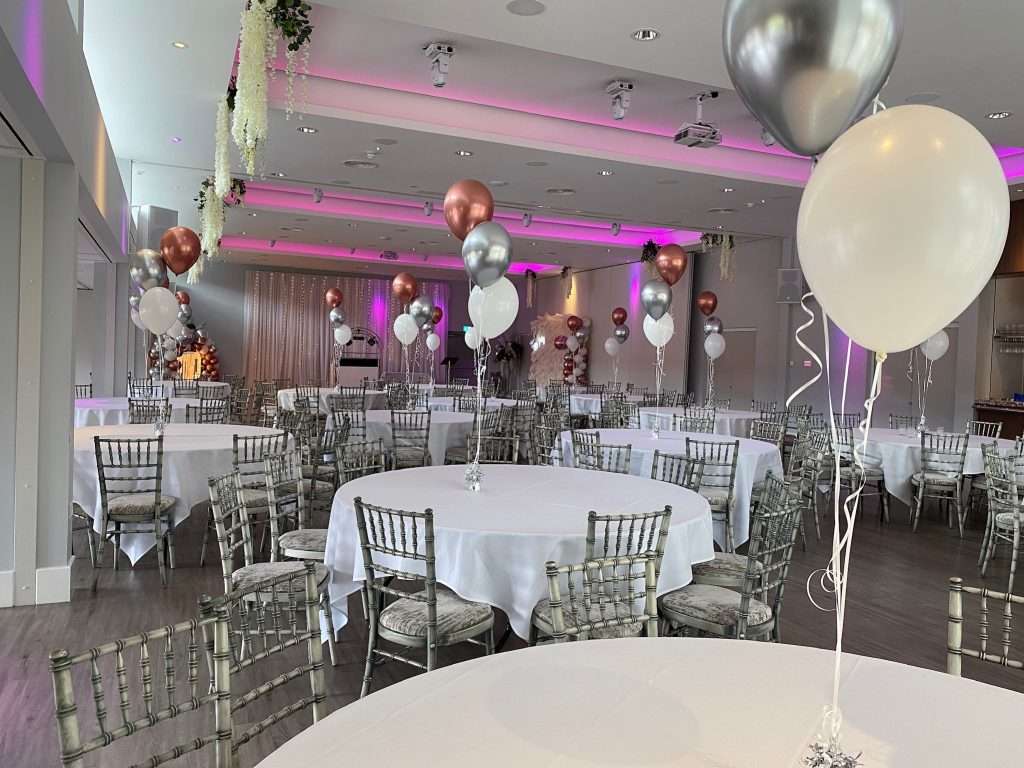 School prom setup in the Garden Suite with pink uplighting and elegant balloon clusters on round tables.