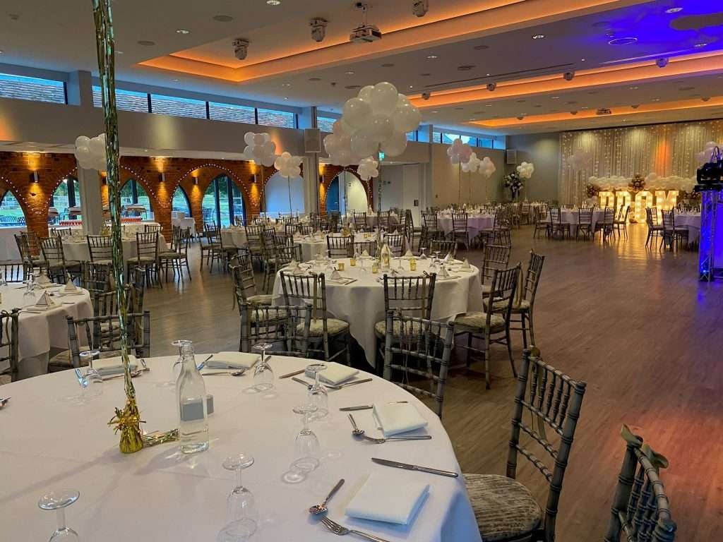 Room view of Garden Suite decorated for school prom with white linen tables and PROM lights in background.