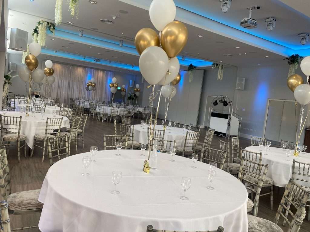 School prom venue with round tables and centrepieces featuring gold and white balloons in the Garden Suite.