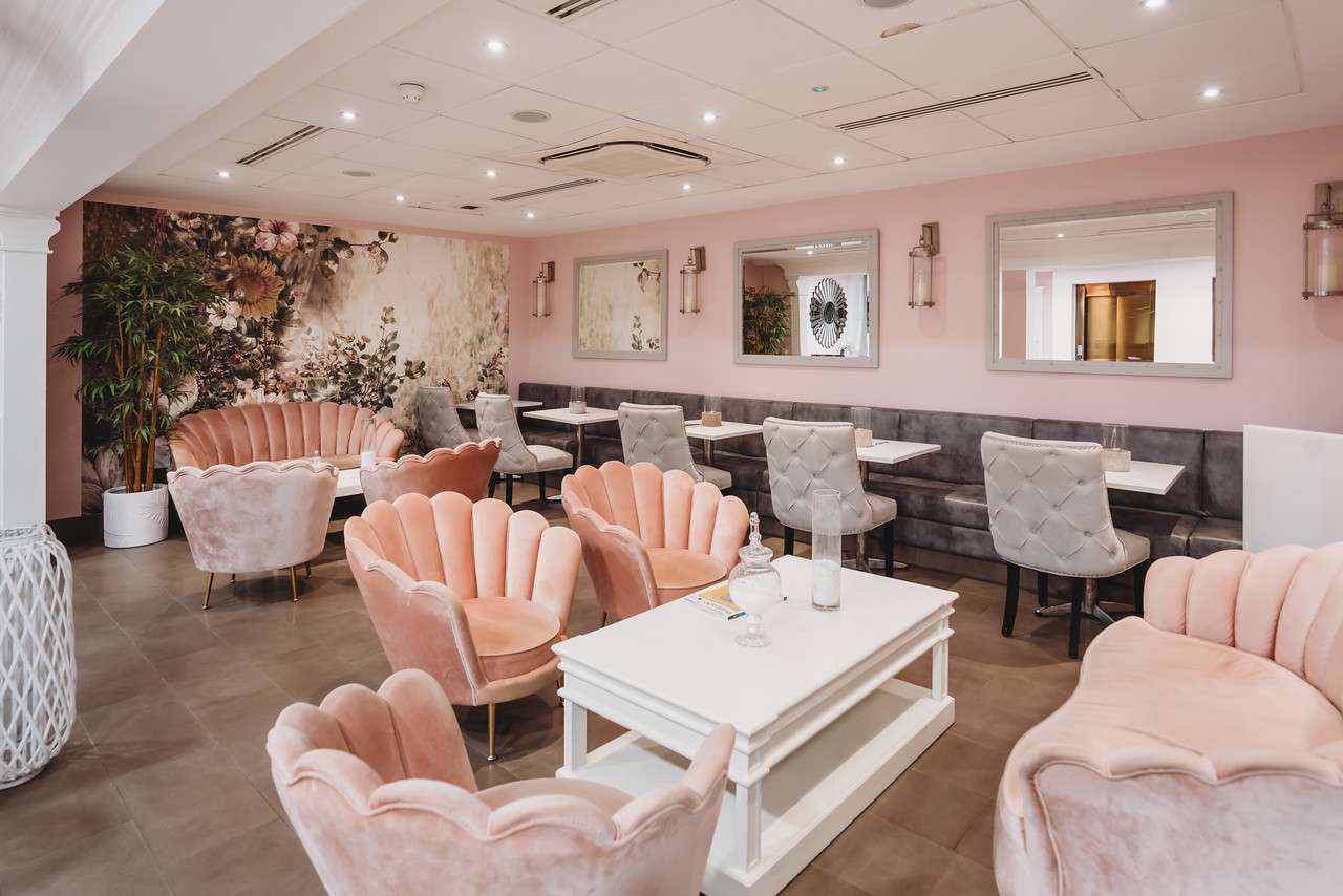 Chic spa reception with velvet chairs, floral feature wall, and elegant décor