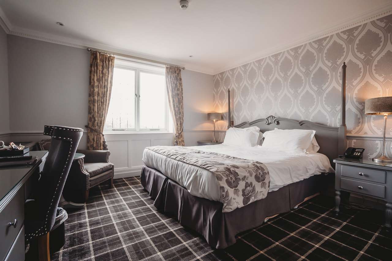 Standard room at Greenwoods Hotel with grey floral bedding and elegant décor