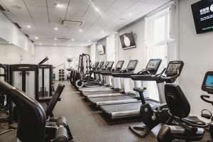 Wide view of the luxury hotel gym at Greenwoods Hotel & Spa showcasing cardio machines, strength equipment, and a spacious fitness layout