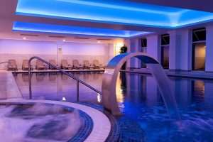 Luxury indoor swimming pool at Greenwoods Hotel & Spa with ambient lighting, relaxation loungers, and a calm spa environment