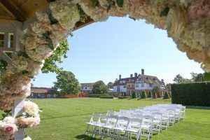Outdoor wedding ceremony setup with white chairs, floral arch and views across Greenwoods Hotel and Spa.
