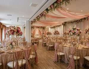 Pink and gold dry hire wedding reception setup with floral centrepieces, draping and luxury table styling at Greenwoods Hotel and Spa.