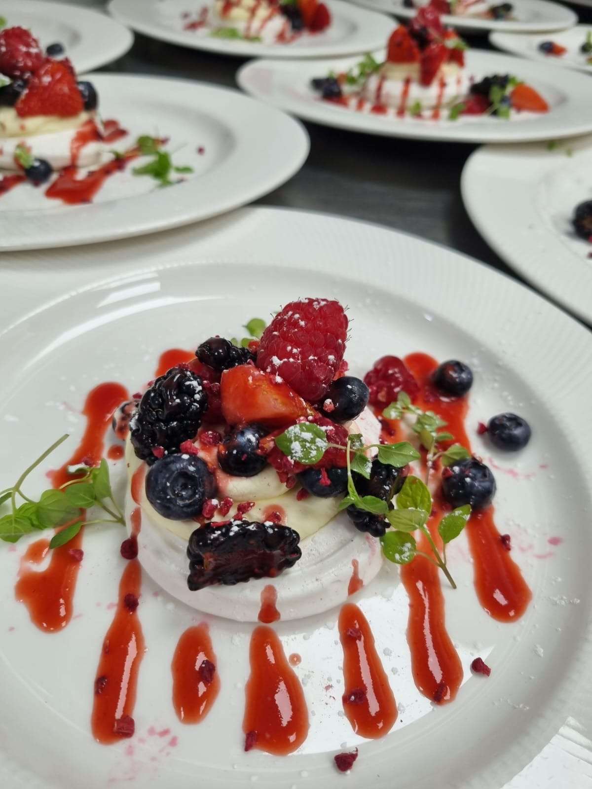 Berry pavlova dessert with raspberries, blueberries, blackberry, strawberry sauce and fresh garnish for a Greenwoods Hotel wedding menu.