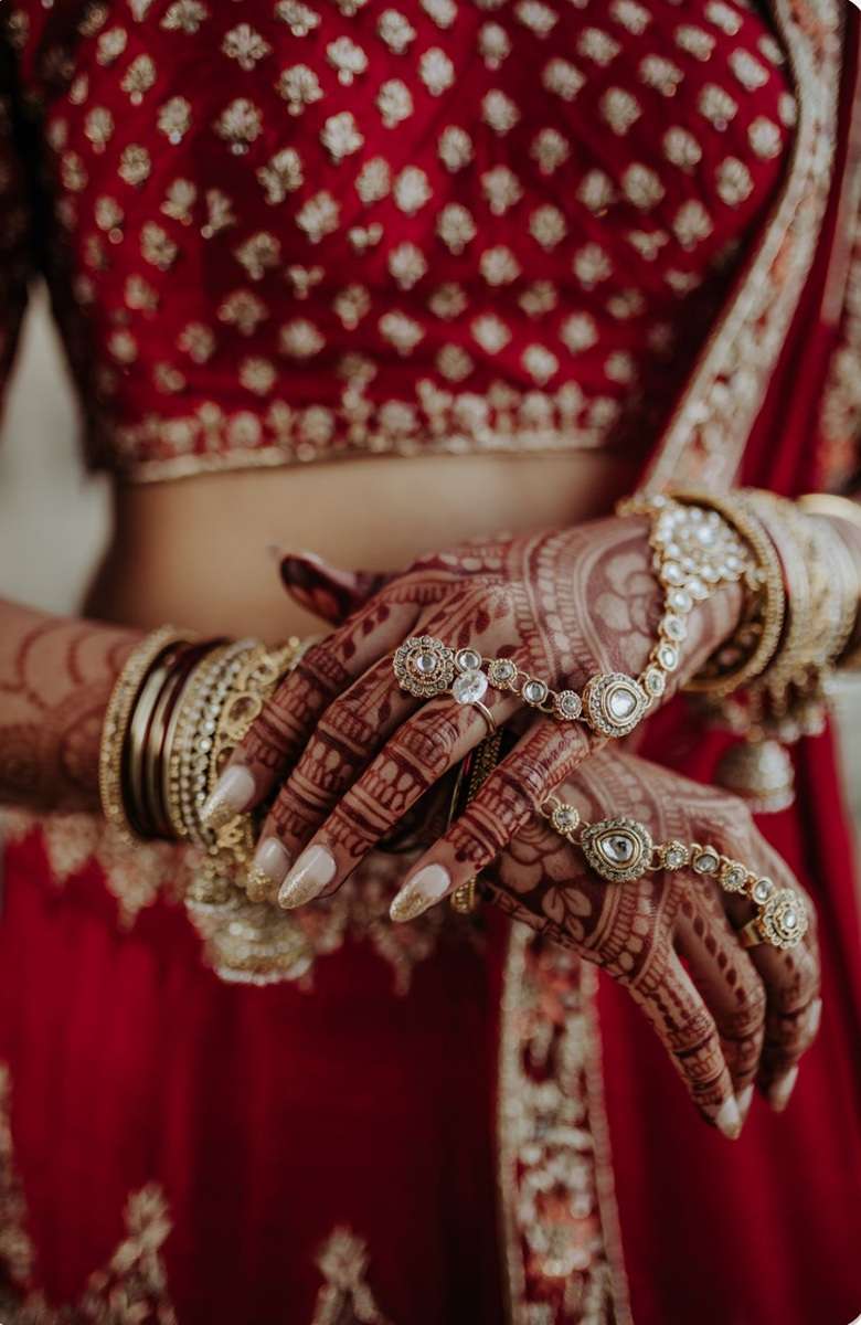 Close-up of bridal mehndi, jewellery and red wedding attire during a cultural dry hire wedding at Greenwoods Hotel and Spa.