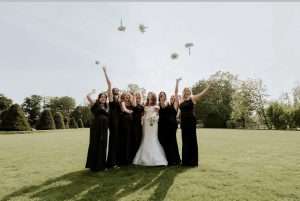 Bride and bridesmaids celebrating with a bouquet toss on the lawns at Greenwoods Hotel and Spa.