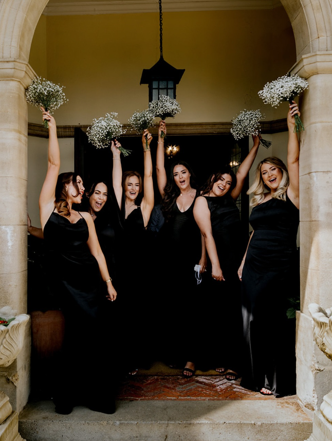 Bridesmaids holding bouquets outside the manor house entrance at Greenwoods Hotel and Spa.