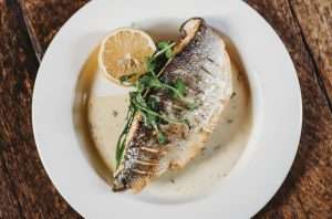 Plated fish dish with lemon and sauce, served as part of a catered wedding menu at Greenwoods Hotel and Spa.