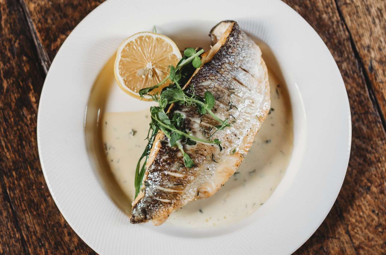 Plated fish dish with lemon and sauce, served as part of a catered wedding menu at Greenwoods Hotel and Spa.