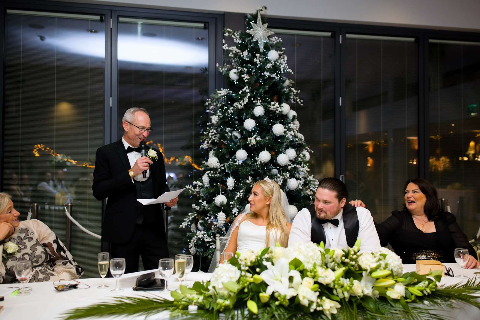 Wedding speech beside a Christmas tree during a festive winter wedding reception at Greenwoods Hotel & Spa in Essex.