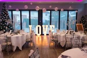 Festive wedding reception setup with illuminated LOVE letters, Christmas tree and elegant table styling at Greenwoods Hotel & Spa in Essex.