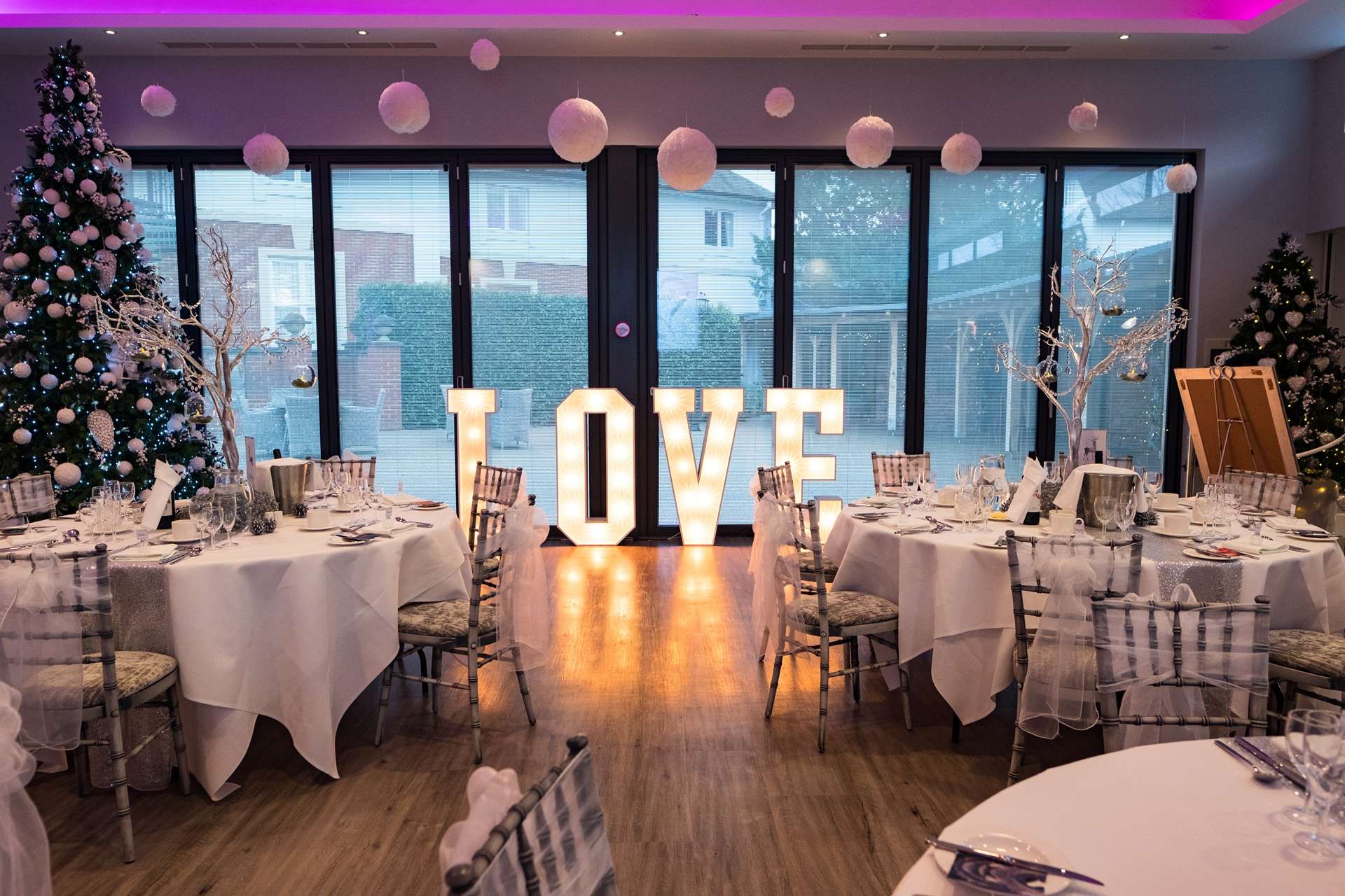 Festive wedding reception setup with illuminated LOVE letters, Christmas tree and elegant table styling at Greenwoods Hotel & Spa in Essex.