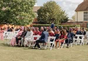 Guests attending an outdoor cultural wedding ceremony in the gardens at Greenwoods Hotel & Spa in Essex.