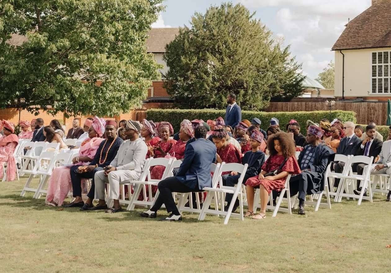 Guests attending an outdoor cultural wedding ceremony in the gardens at Greenwoods Hotel & Spa in Essex.
