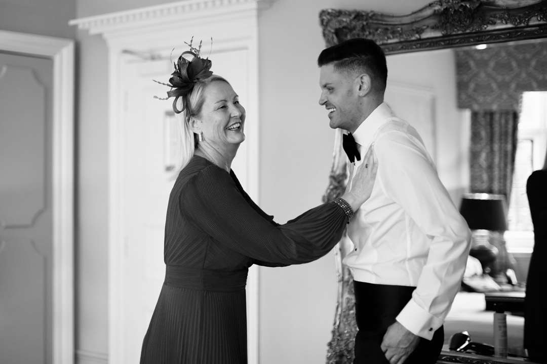 Groom smiling during wedding morning preparations in a hotel bedroom at Greenwoods Hotel and Spa.