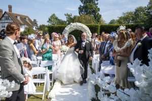 Bride walking down the aisle during an outdoor wedding ceremony at Greenwoods Hotel and Spa in Essex.
